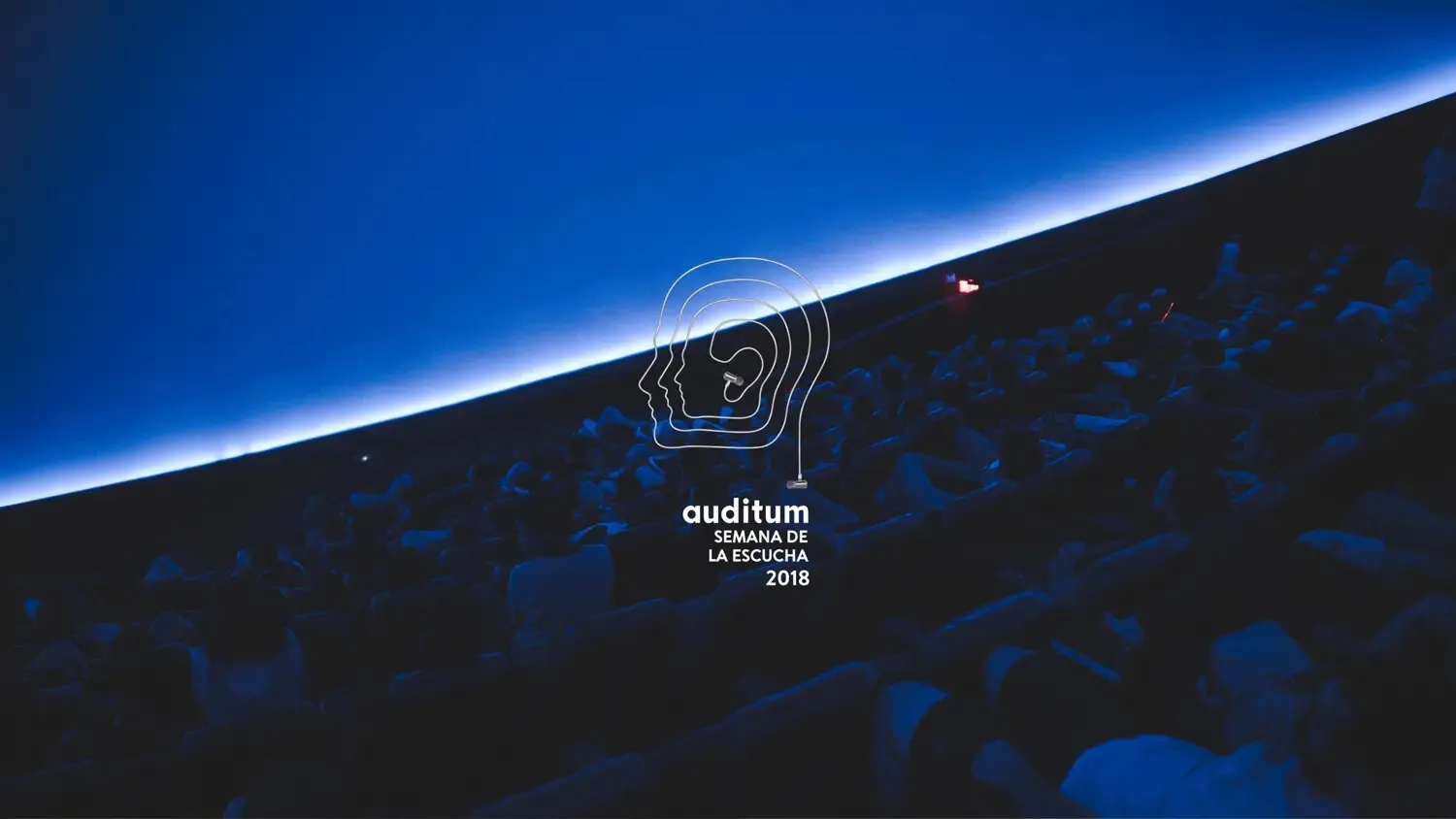 Un público oscurecido bajo una cúpula de proyección azul profunda, con el logo Auditum Semana de la Escucha 2018 en blanco.