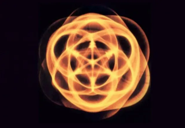 Un mandala naranja brillante de luz sobre negro, un patrón cimático