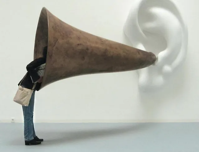 Una persona escuchando a través de una trompeta gigante en forma de cuerno