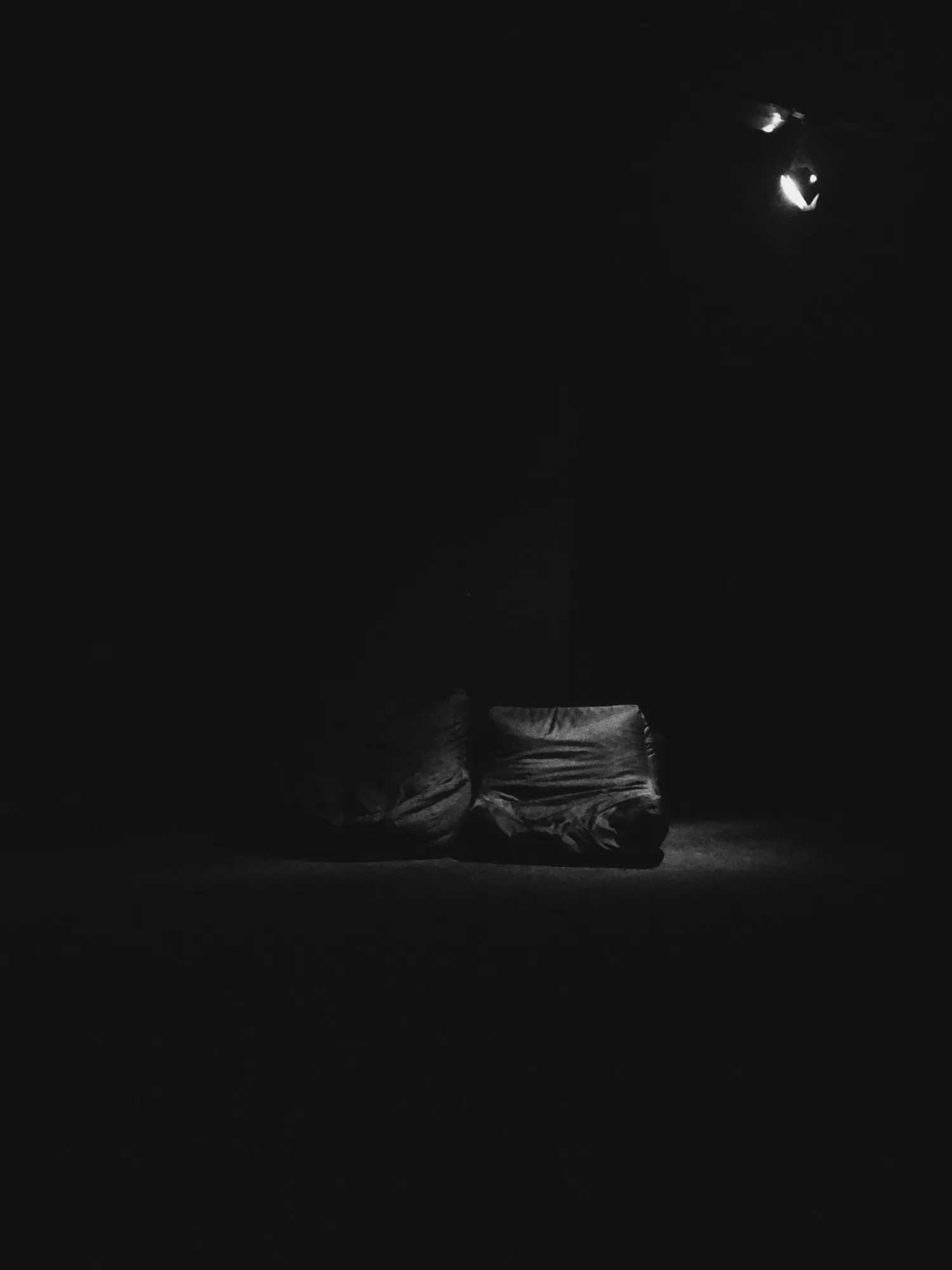 Una habitación oscura con un solo sillón bajo iluminado por un foco, el espacio de escucha de la instalación.